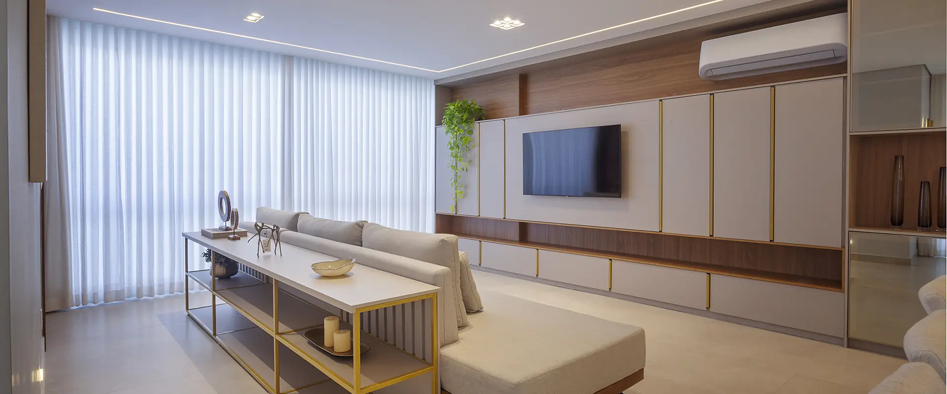Sala integrada com painel amadeirado e aparador dourado