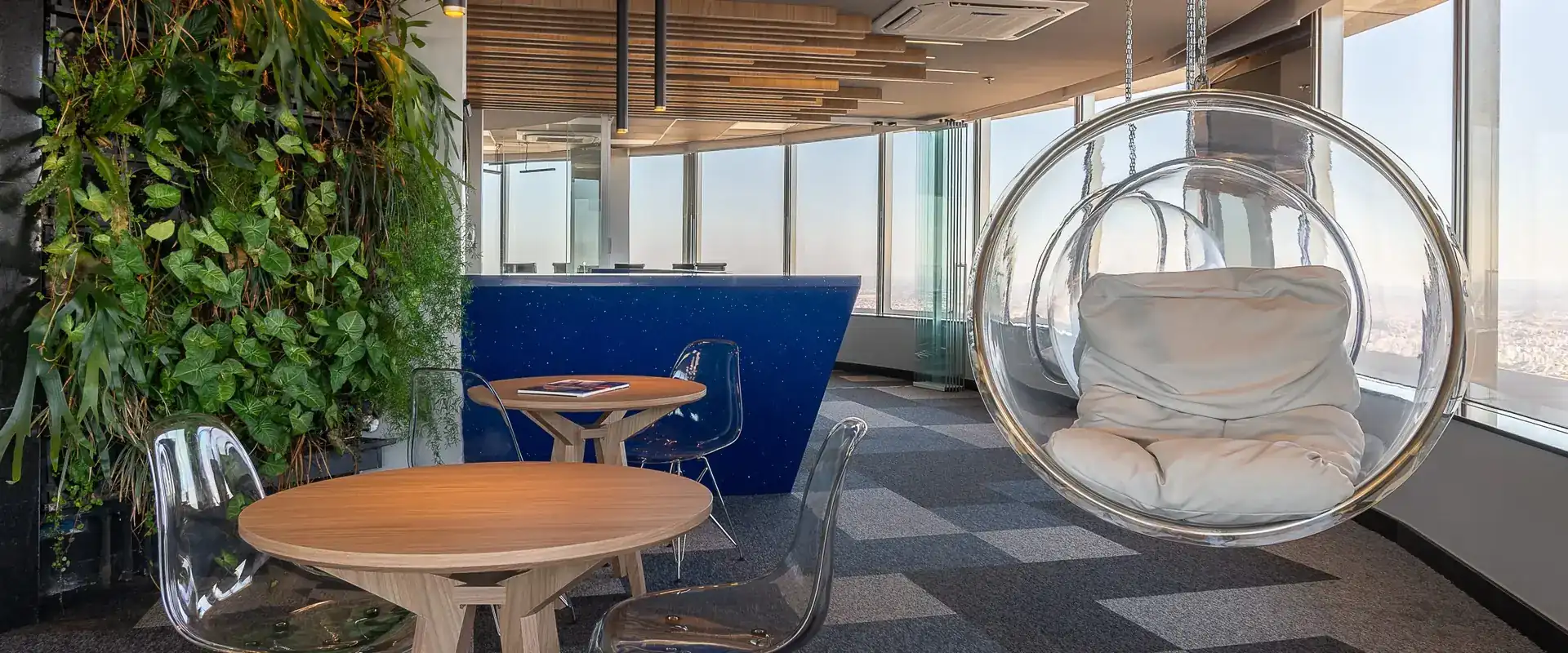 Escritório corporativo com jardim vertical e poltrona suspensa