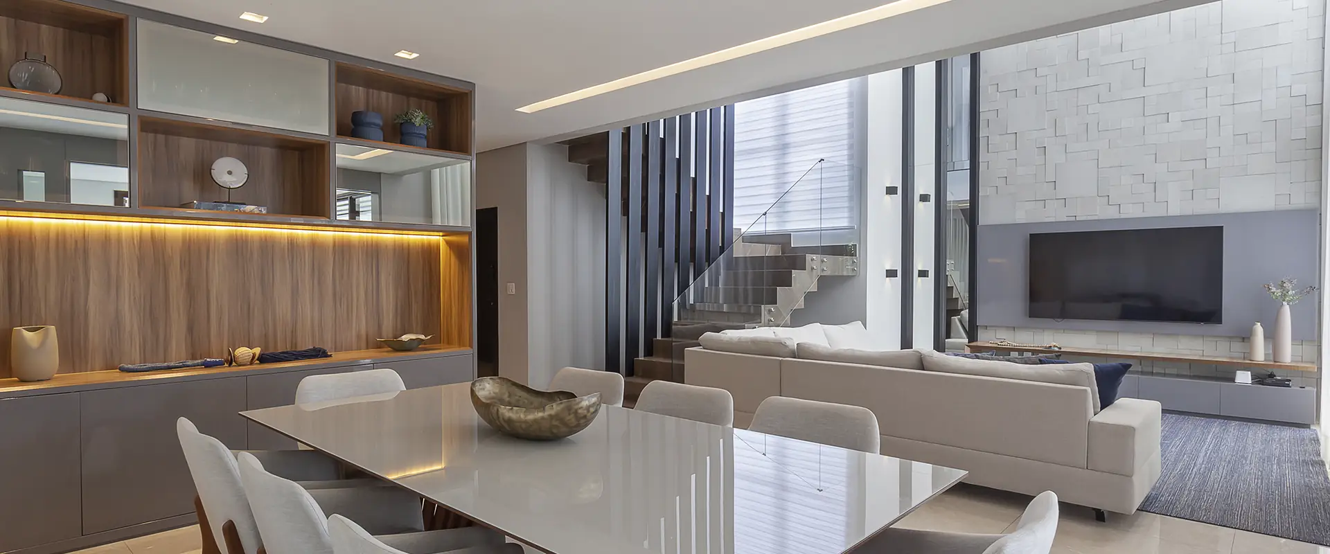 Living com escada, sala de jantar e estante iluminada
